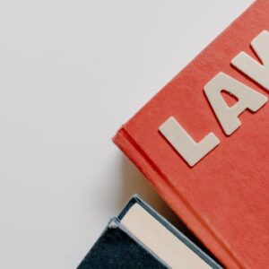 Red law textbook and dark book on white background, symbolizing education.
