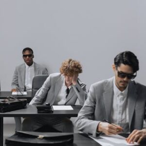 Three men in gray suits writing an exam indoors. Focus on business attire and concentration.