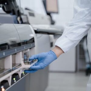 Lab technician in a white coat using equipment with precision in a sterile environment.