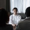 A social worker talks to a diverse couple in a home setting.