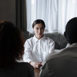 A social worker talks to a diverse couple in a home setting.