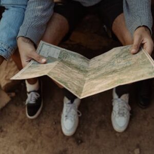 Close-up of a group exploring a map, planning a travel adventure while sitting outdoors.