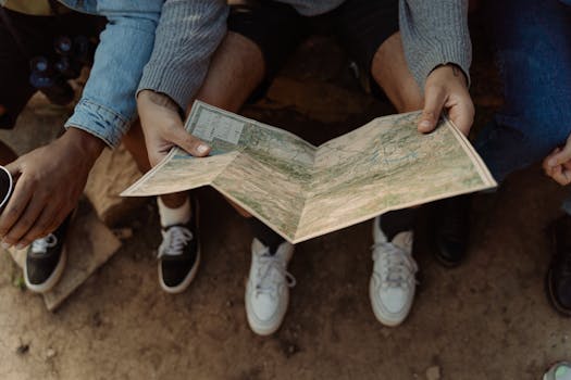 Close-up of a group exploring a map, planning a travel adventure while sitting outdoors.