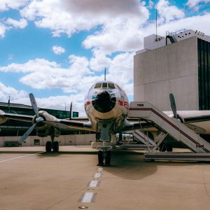 Retro TWA airplane on tarmac with terminal backdrop under blue sky in New York.