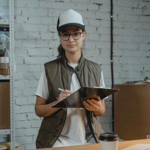 Young woman with clipboard in a warehouse, managing inventory with precision.