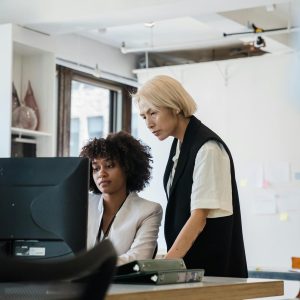 Two employees collaborating at a desk in a bright, modern office environment.