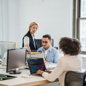 Business team working collaboratively in a modern office setting with computers and laptops.