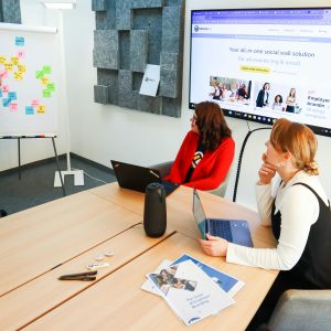 Three women collaborate in a conference room using digital tools for effective teamwork.