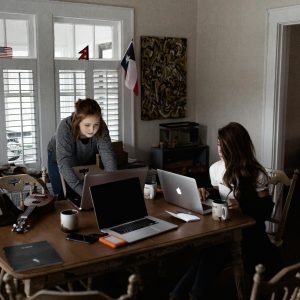 Two young women working collaboratively in a cozy home office setting.