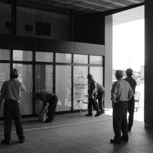 Workers maintaining cleanliness at a Japanese station in black and white.