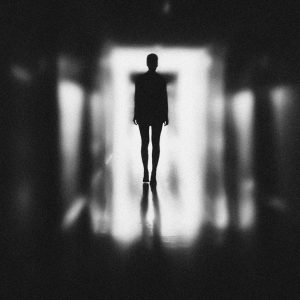 Moody silhouette of a person in a blurred, black and white corridor. Capturing themes of solitude and mystery.