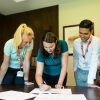 Three colleagues collaborating on a project around an office table, fostering teamwork and cooperation.