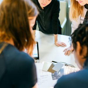 A group of adults engaged in teamwork and planning at an indoor office meeting.
