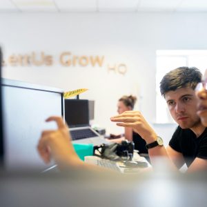 Focused co-workers collaborating in a modern office environment, discussing a project on computer screens.