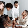 A diverse group of professionals engaged in a team discussion in a modern office setting.