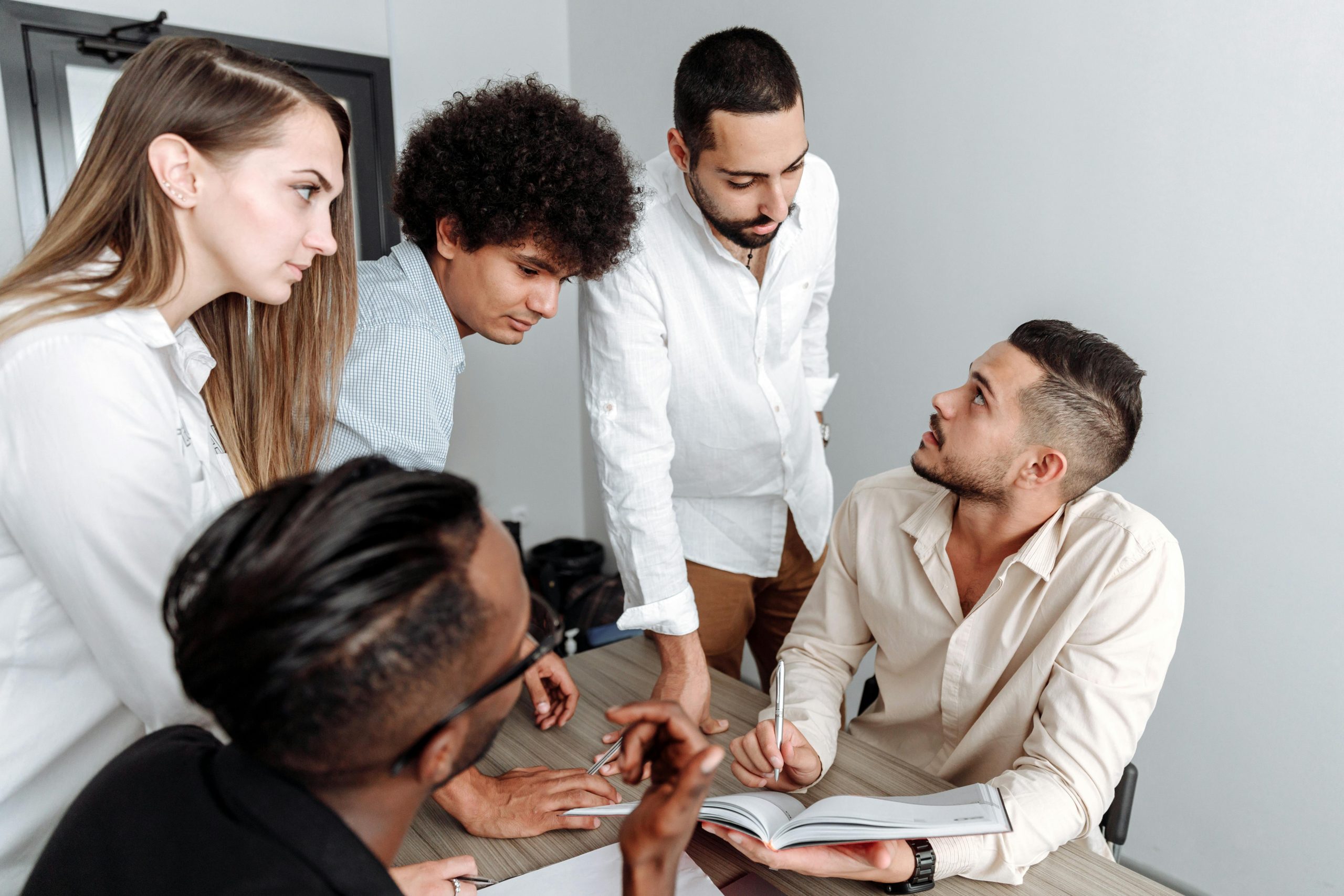 A diverse group of professionals engaged in a team discussion in a modern office setting.