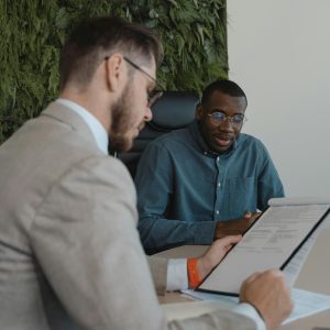 Two men in a modern office setting discussing a document during a business meeting.