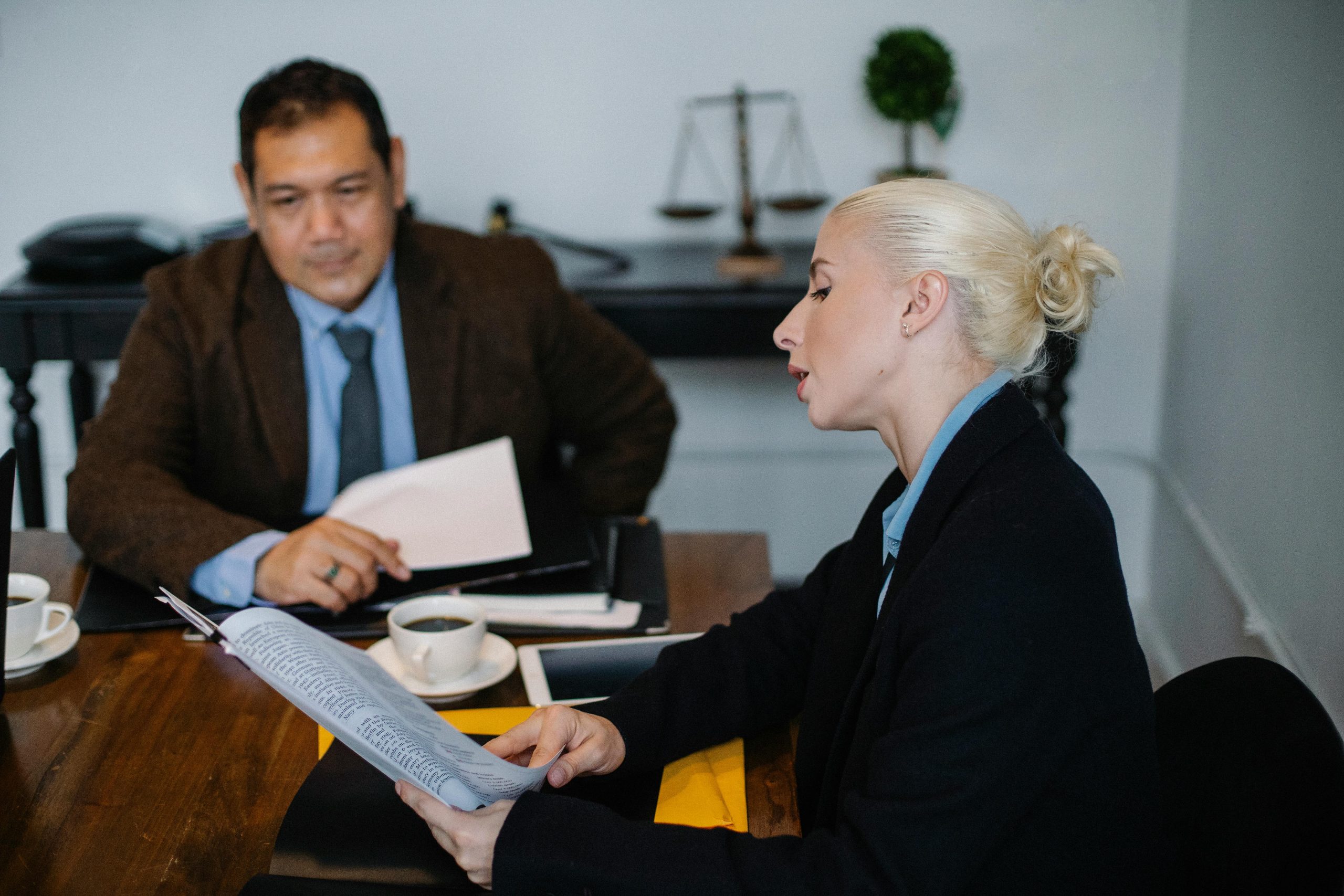 Two business professionals discussing documents during a meeting in an office setting.