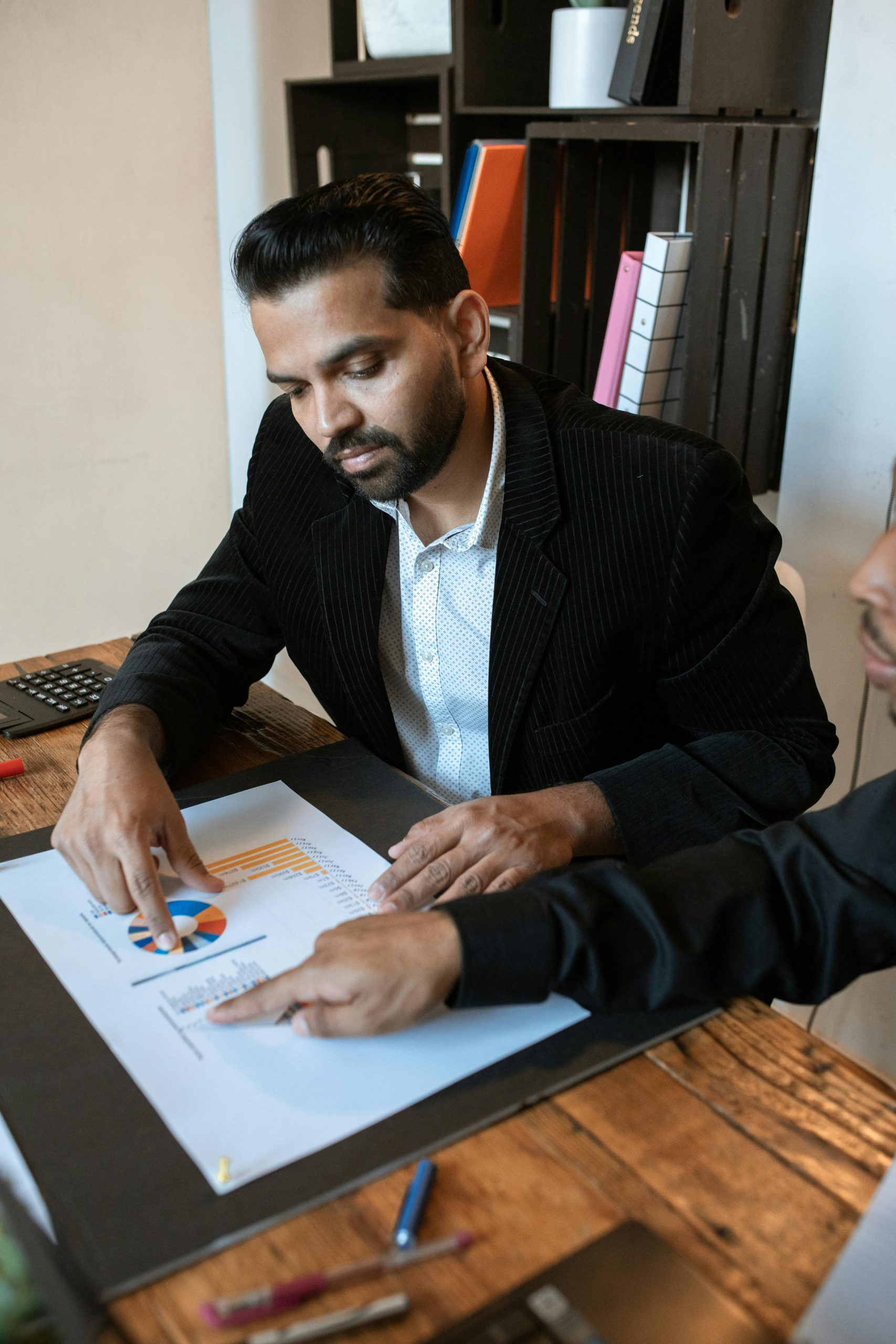 Two professionals discussing a business graph at an office desk.