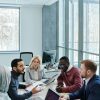 A diverse group of colleagues working together on a project in a bright, modern office environment.