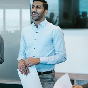 Smiling businessman holding papers during an office meeting.