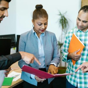 A group of professionals discussing documents in an office meeting, showcasing teamwork and collaboration.