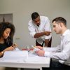 Manager instructing employees during a focused team meeting in a modern office setting.