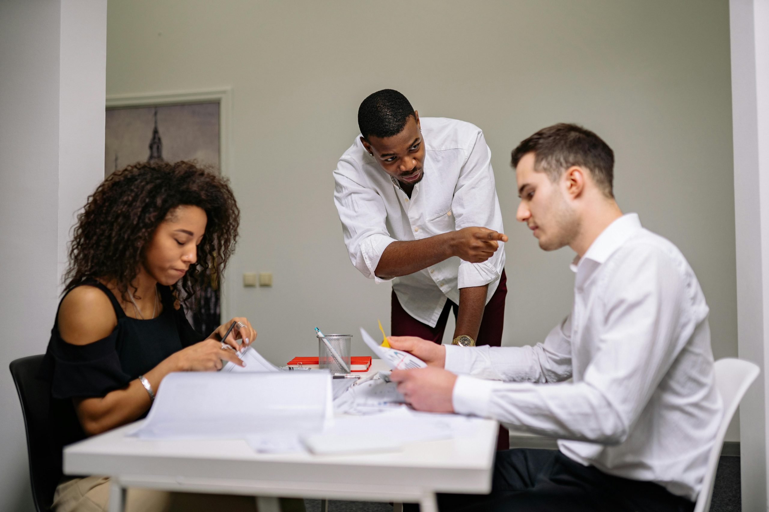 Manager instructing employees during a focused team meeting in a modern office setting.