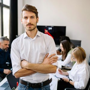 Businessman stands confidently with team in a modern office environment.