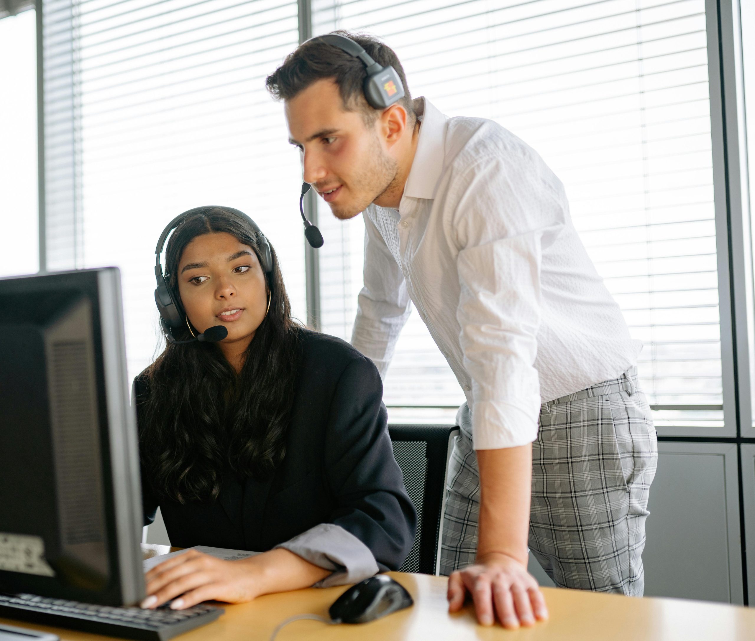 Two customer support agents working together in an office setting.