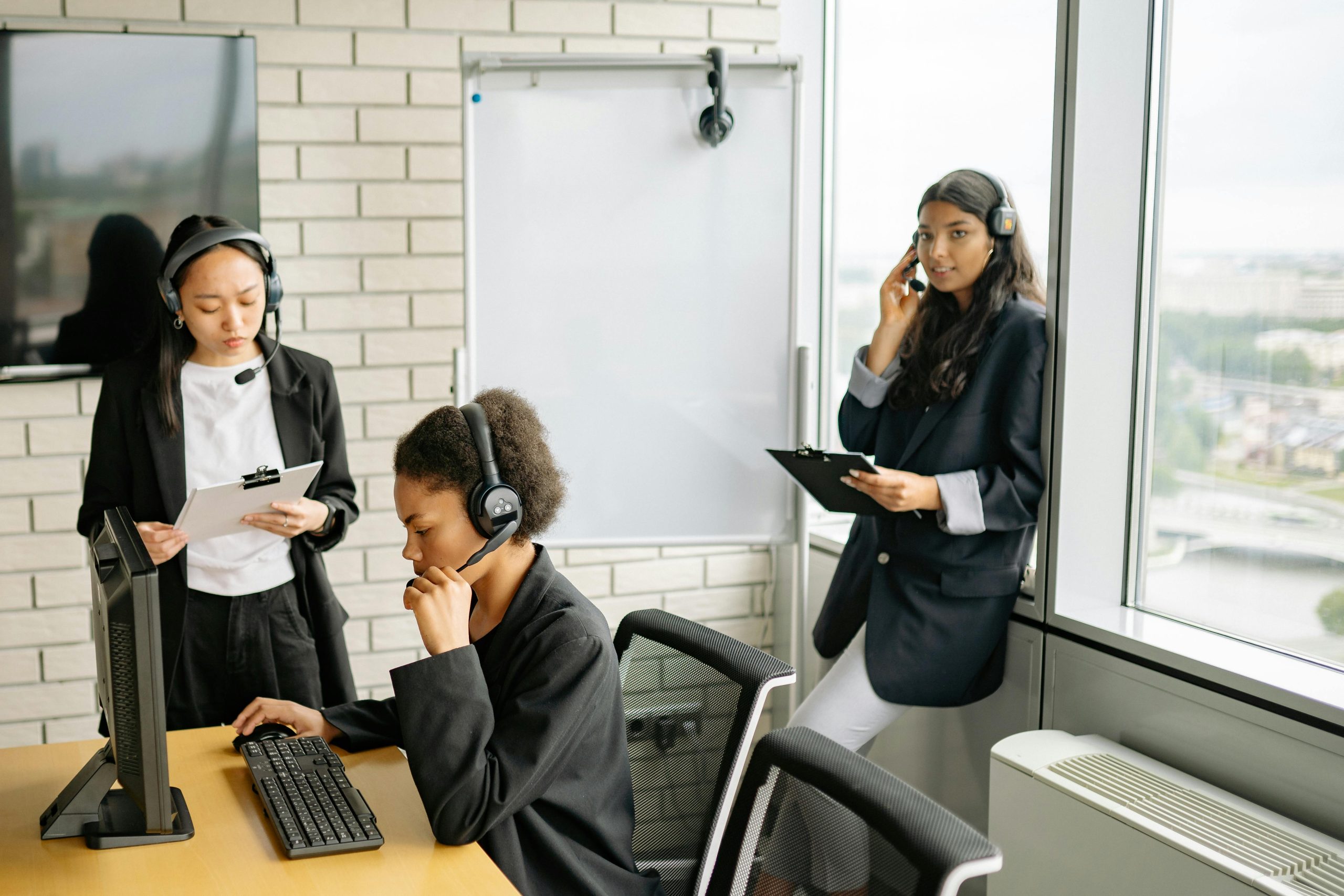 Professional women collaborating in a call center with headsets and computers.