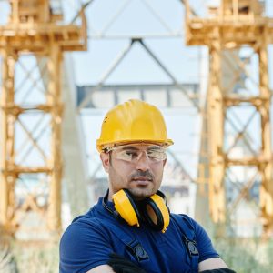 Confident engineer standing with protective gear at a construction site.