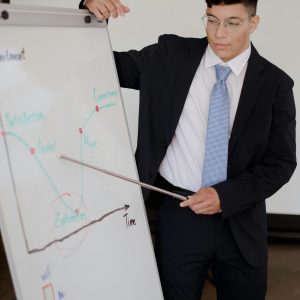Man in suit giving a business presentation with graphs in an office setting.