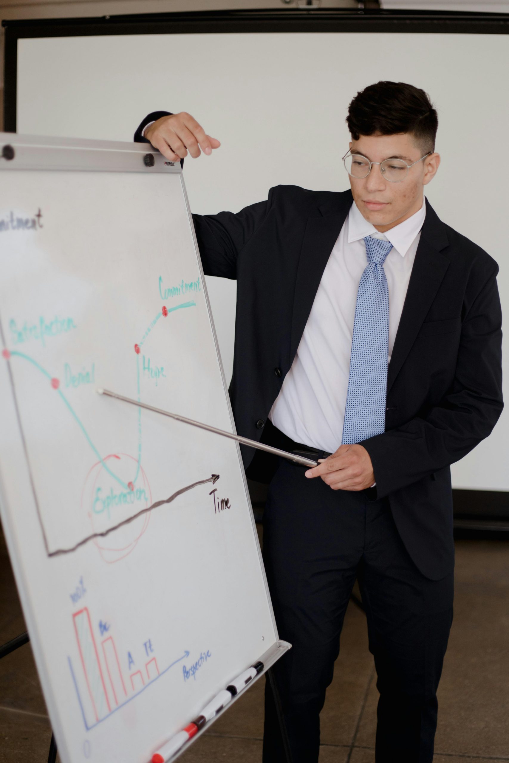 Man in suit giving a business presentation with graphs in an office setting.