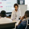 Business meeting with team discussing strategy, led by a professional woman in an office.